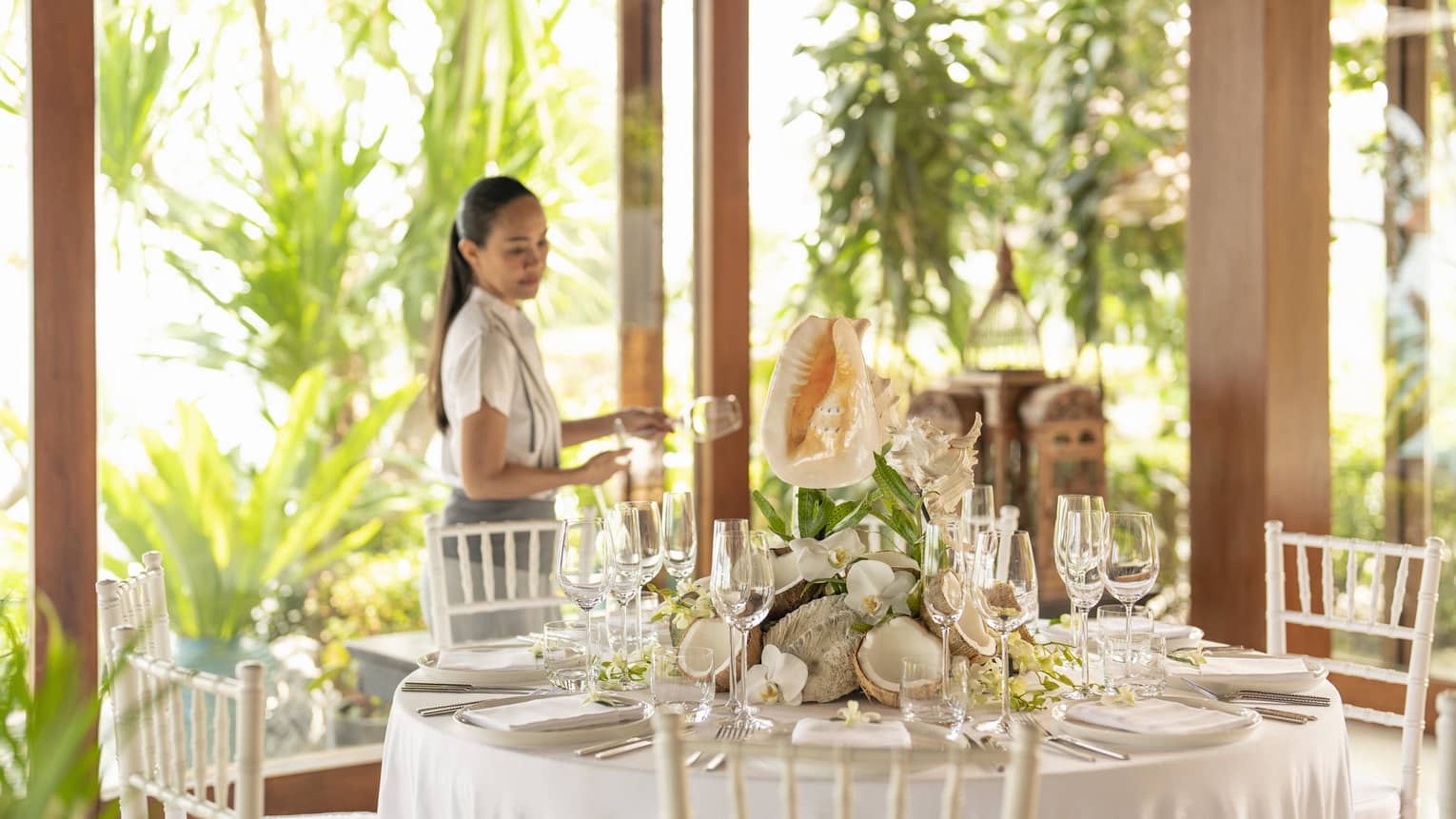 Female staff member sets table with large conch shell centrepiece for a banquet