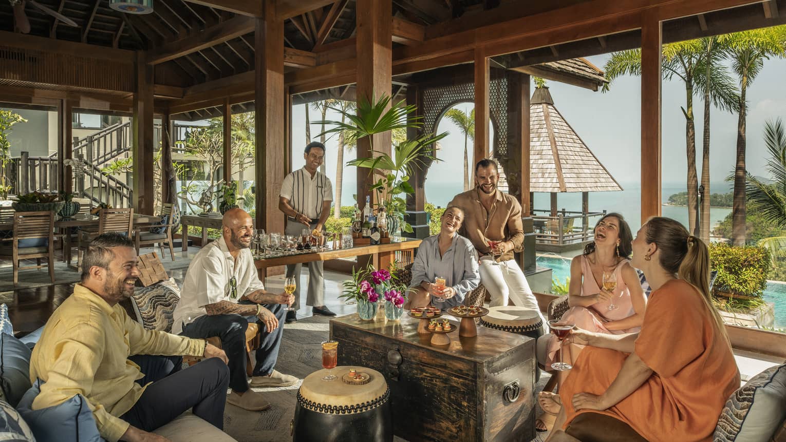Laughing group of friends enjoy drinks made by their private bartender