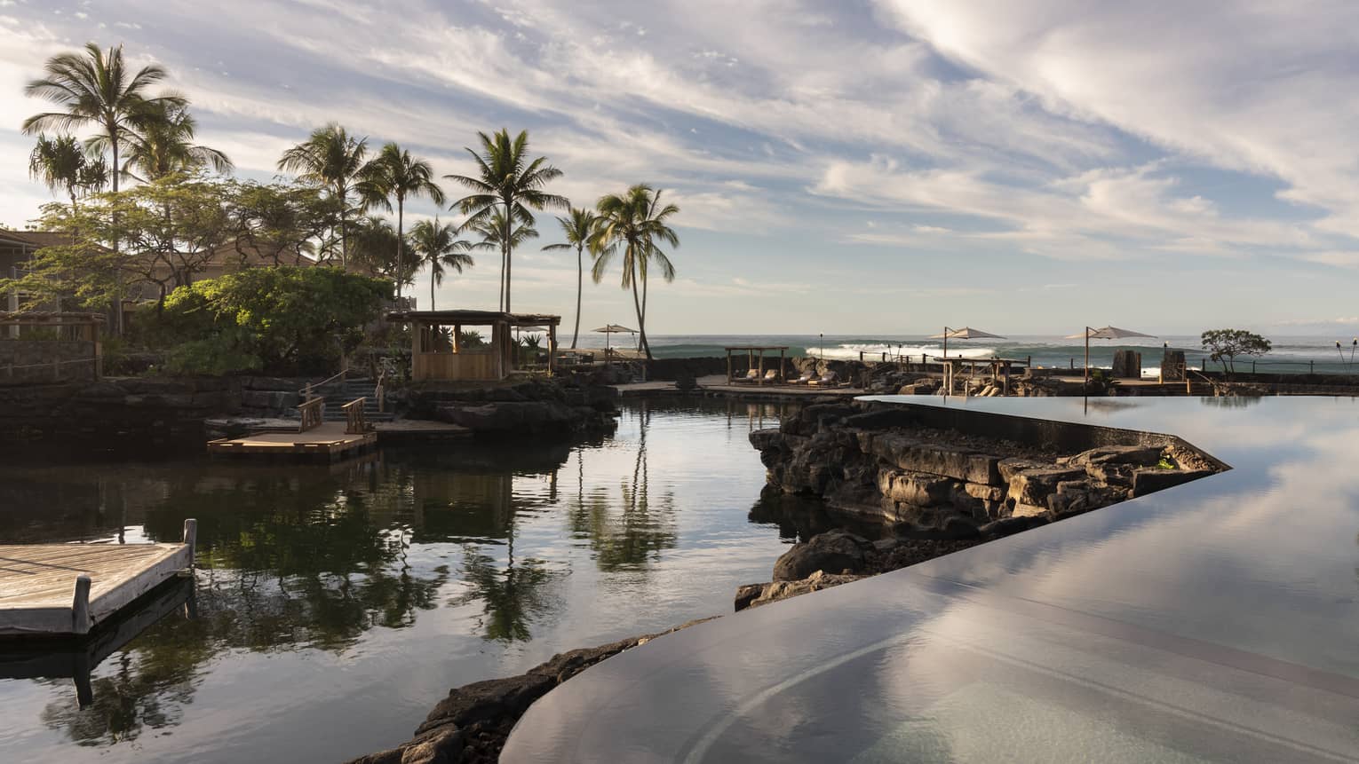Resort pool that mimics a curved pond, palm trees in distance