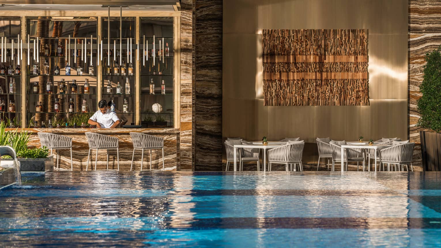 Pool bar and grill with view of pool and bartender