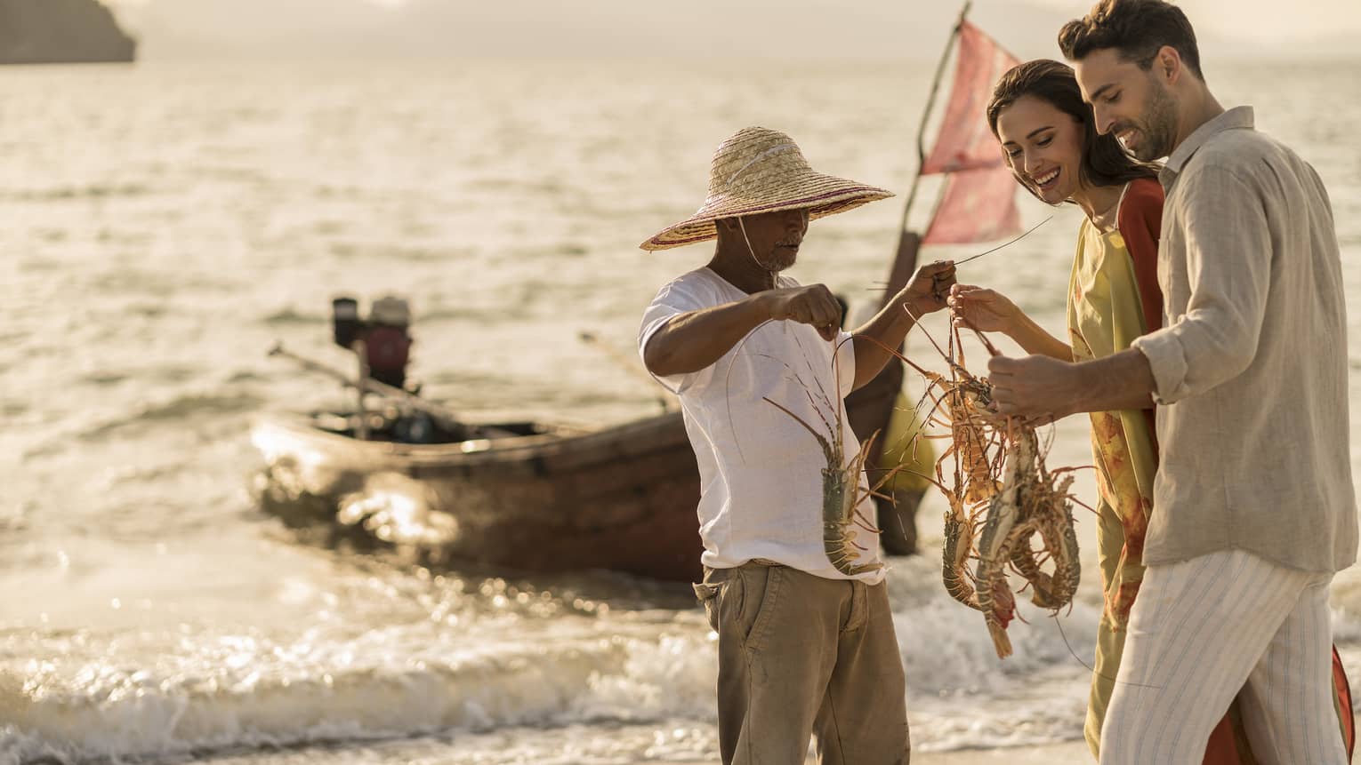 A four seaons fishing guide is holding and showing 4 lobsters to a man and a woman
