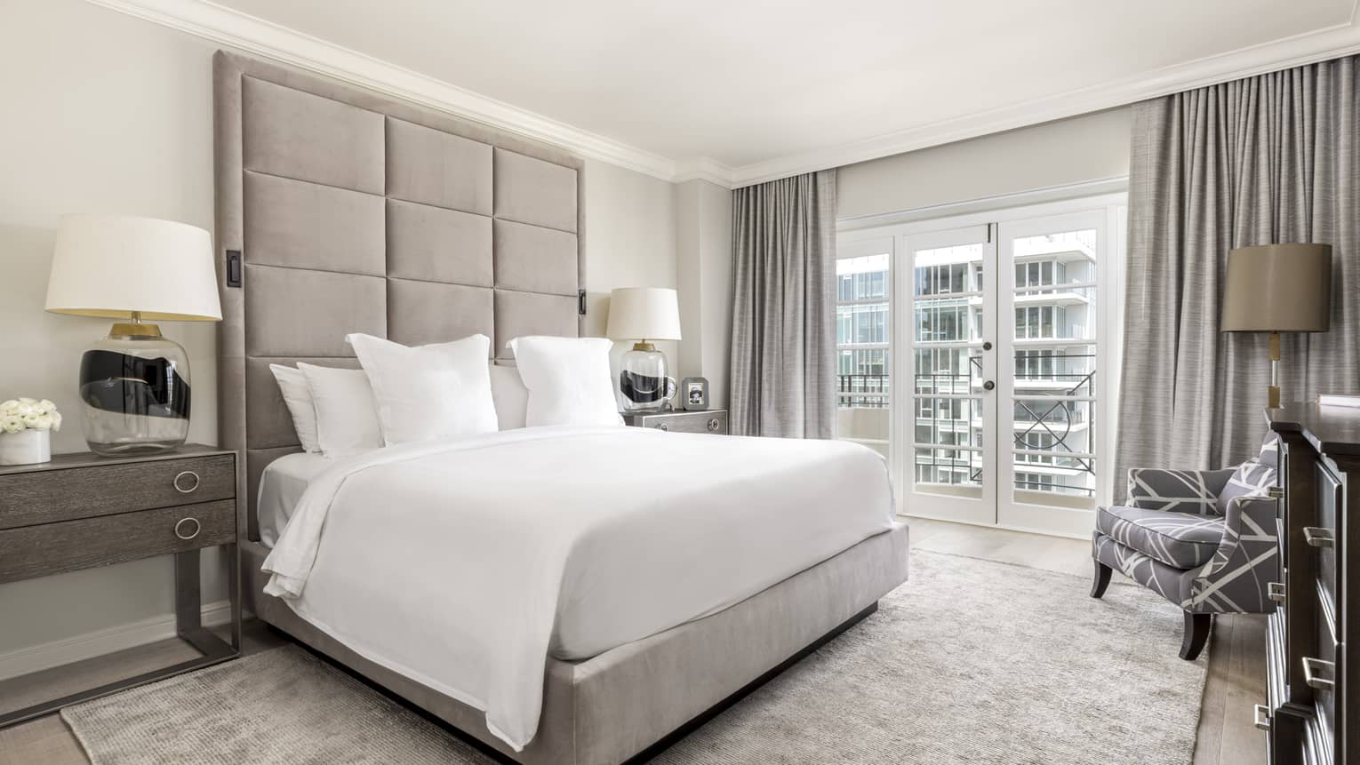 Bedroom with king bed, white sheets, ceiling-height upholstered headboard