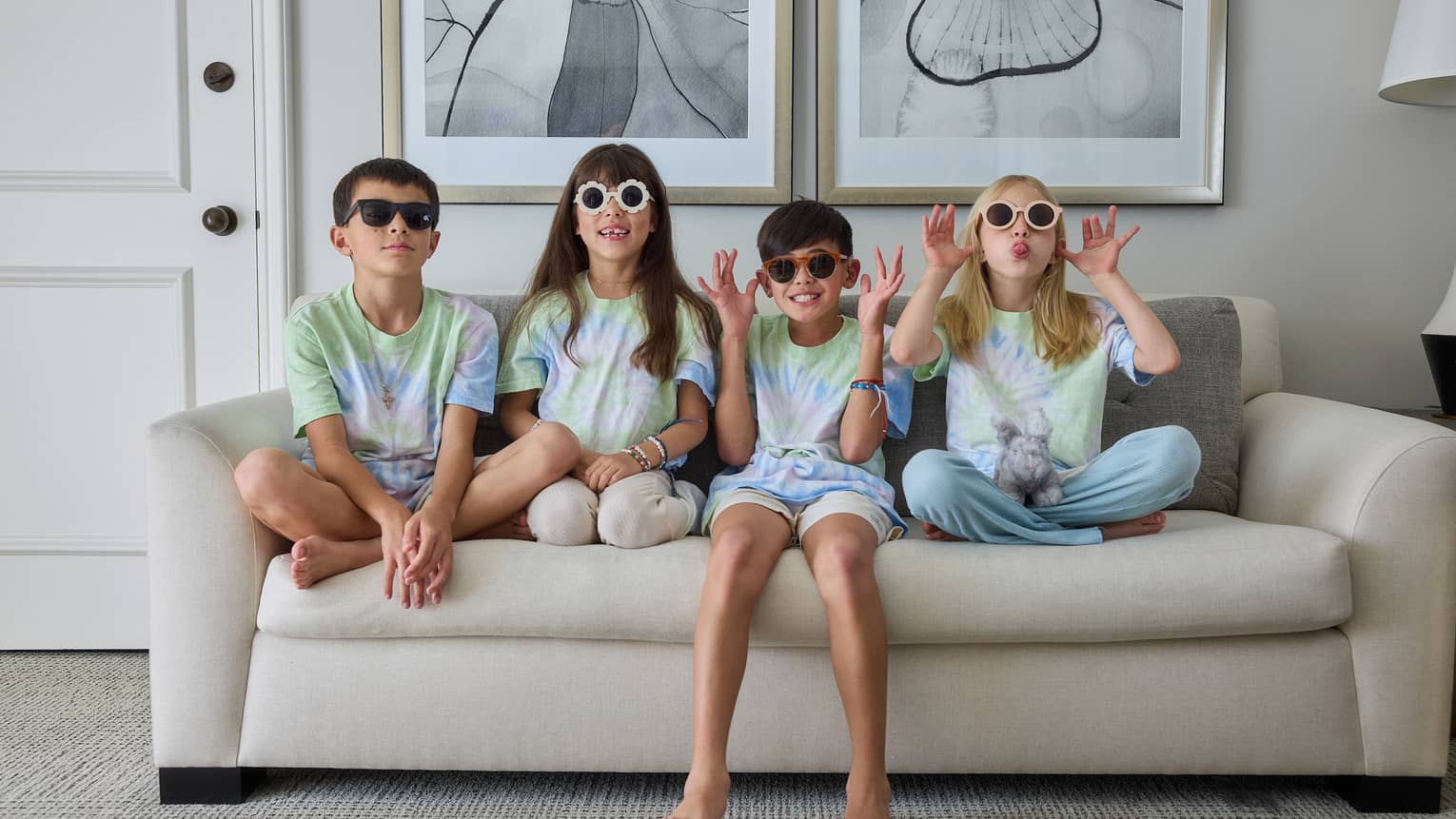 Four young guests sitting beside each other on a couch and wearing sunglasses