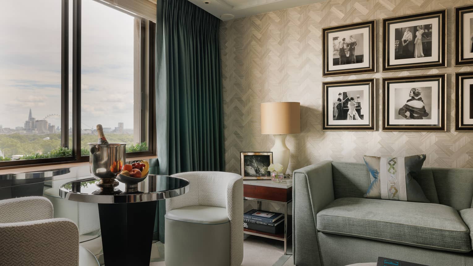 Luxury hotel suite at Four Seasons Hotel London at Park Lane, featuring a stylish living room with a sofa, round table with two chairs and six framed photos on the wall