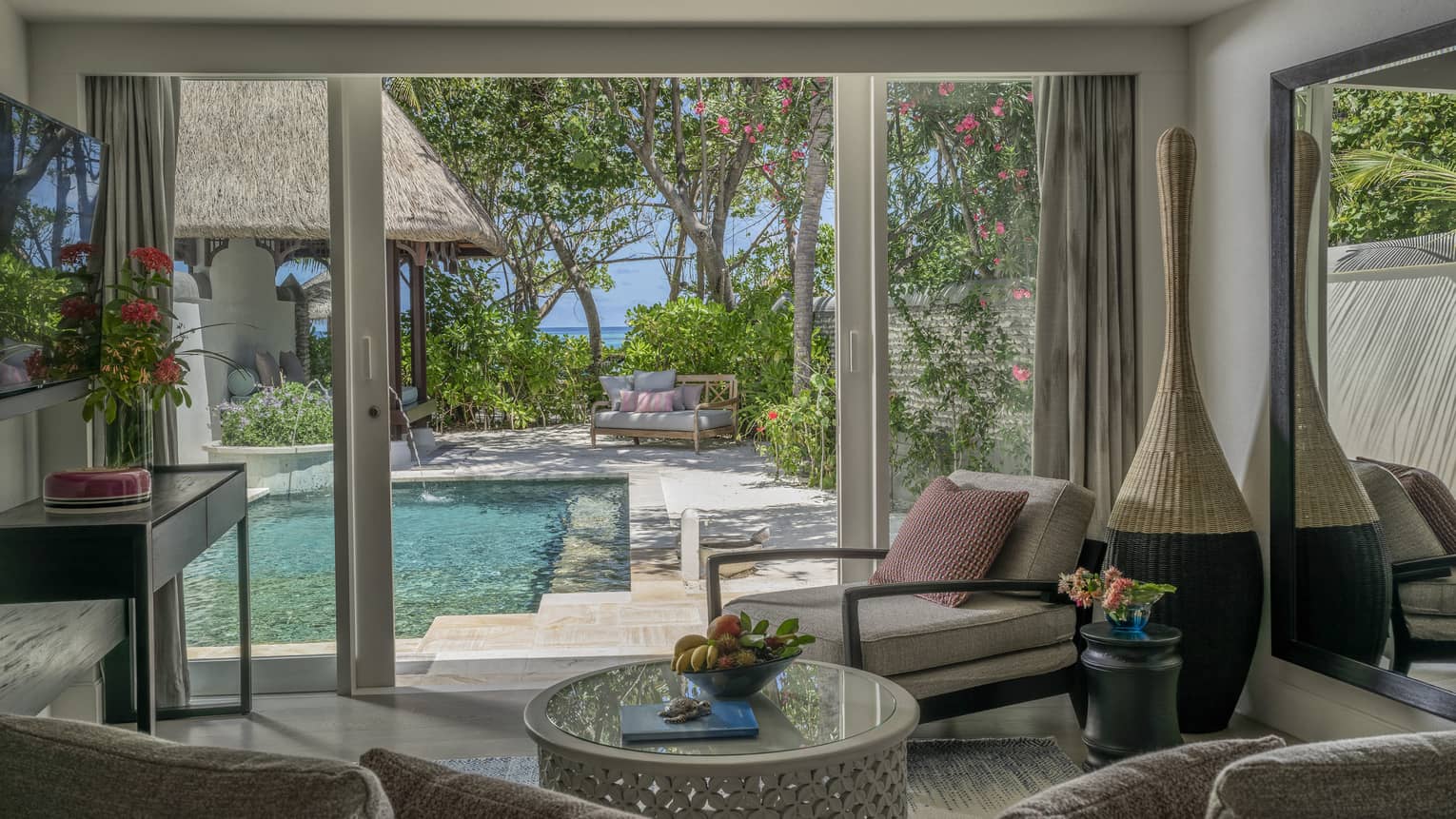 Living room opening to pool deck, with beach in the distance