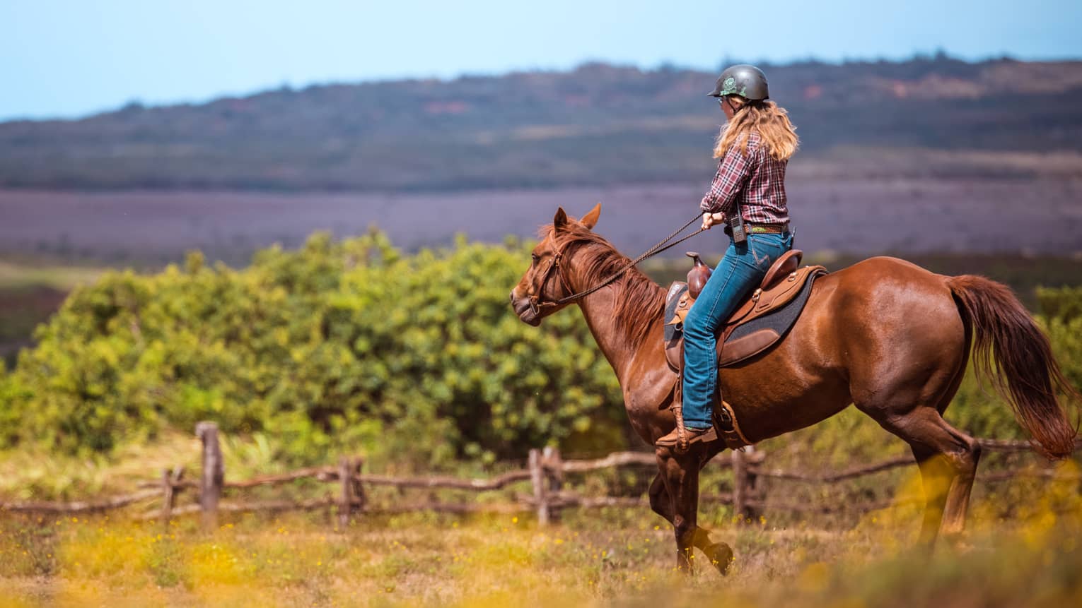 A woman horseback riding in a mountain landscape