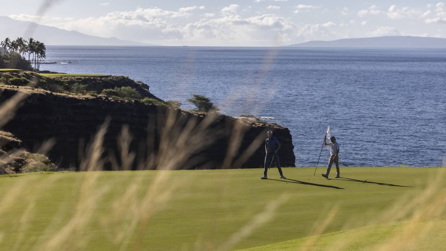 Two golfers on oceanside green at Four Seasons Resort Lanai