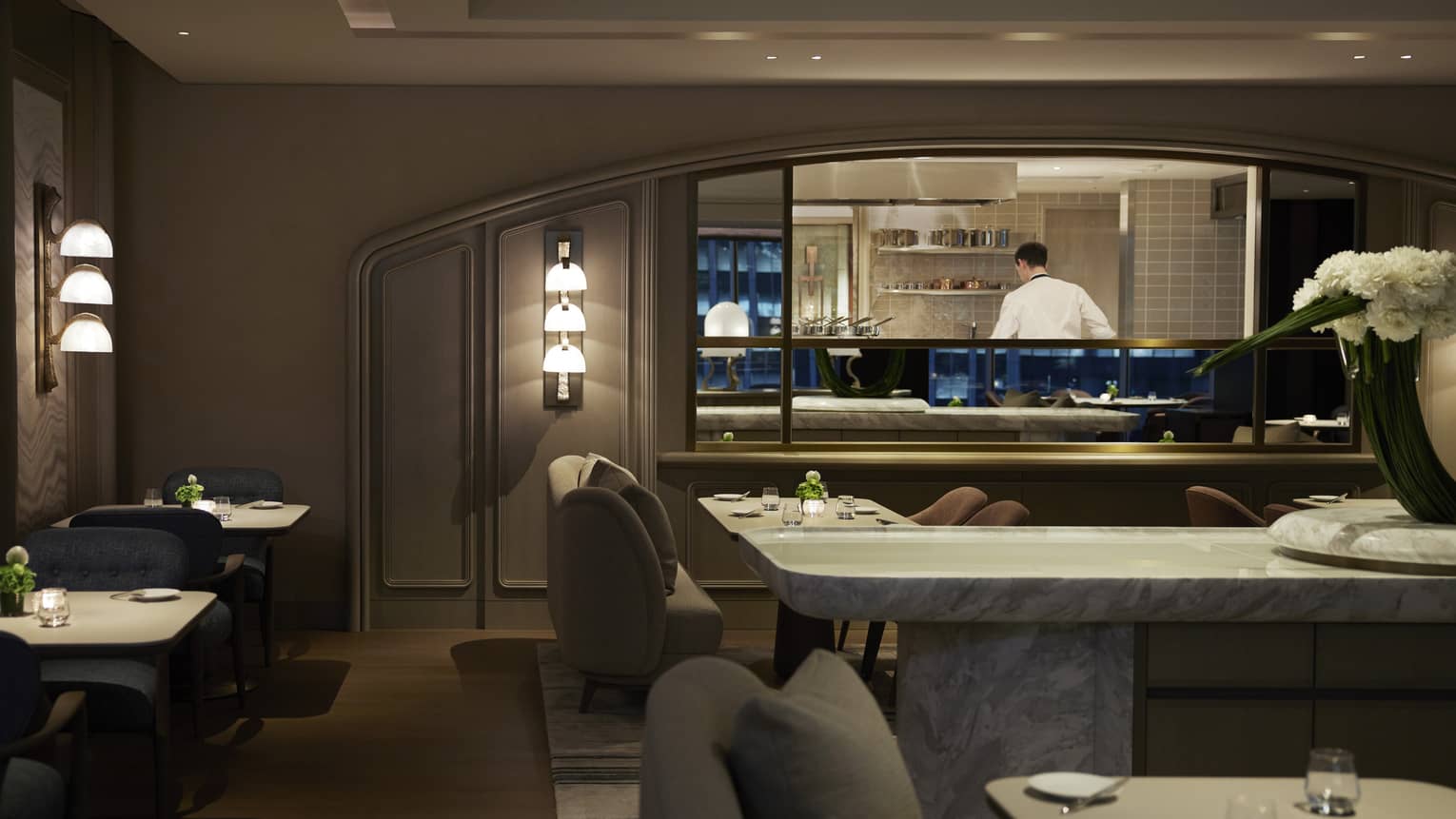 Dimly lit intimate dining area with lighted wall sconces, dark grey colour scheme