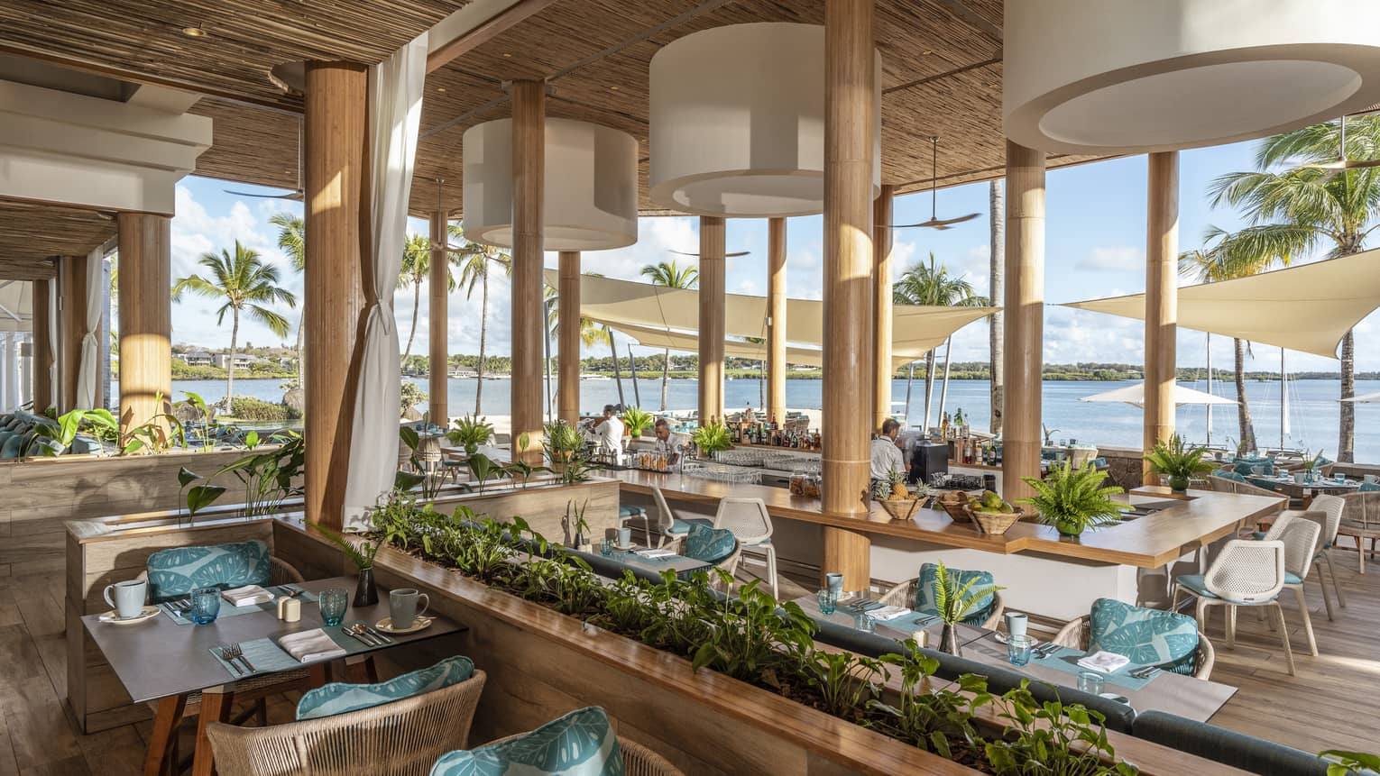 Large open-air restaurant with bamboo chairs, blue décor and water view