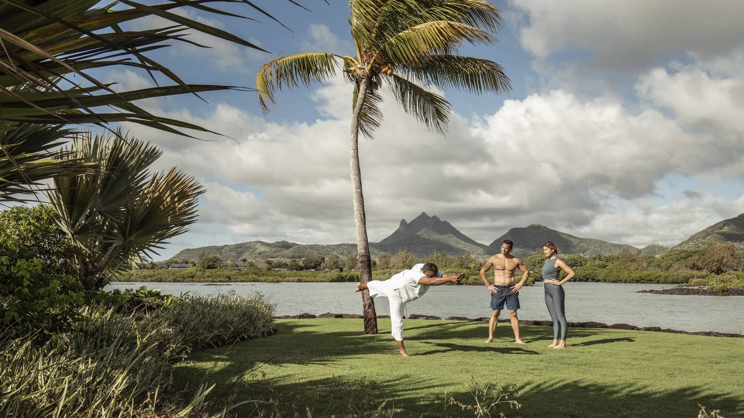 Yogi master teaches couple's yoga class beachside