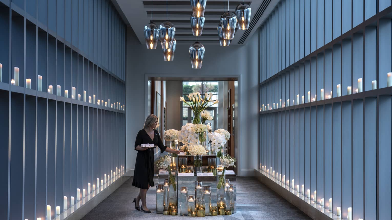 Hotel staff sets table with large flower arrangements in modern Sky Bridge