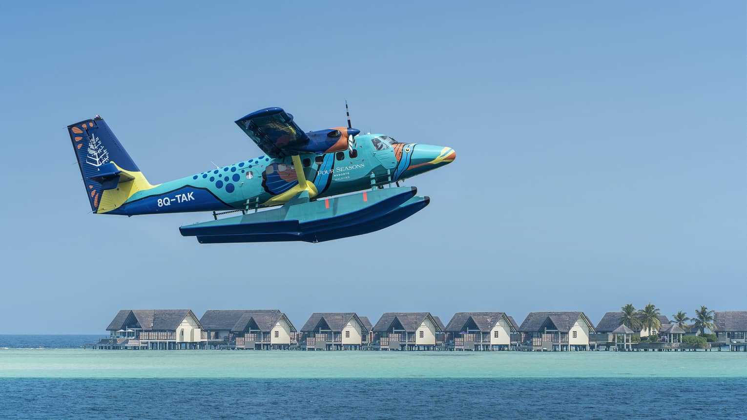 Maldives Sea Plane taking off with water villas and palm trees in the background