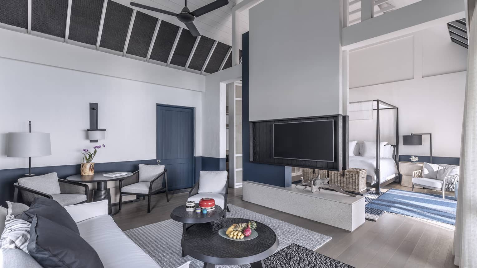A brightly lit, cozy living room with a television, couch and access to the bedroom