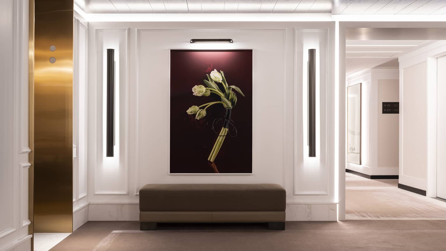 White grand foyer with over-sized painting of white flowers with purple background, below a brown sofa
