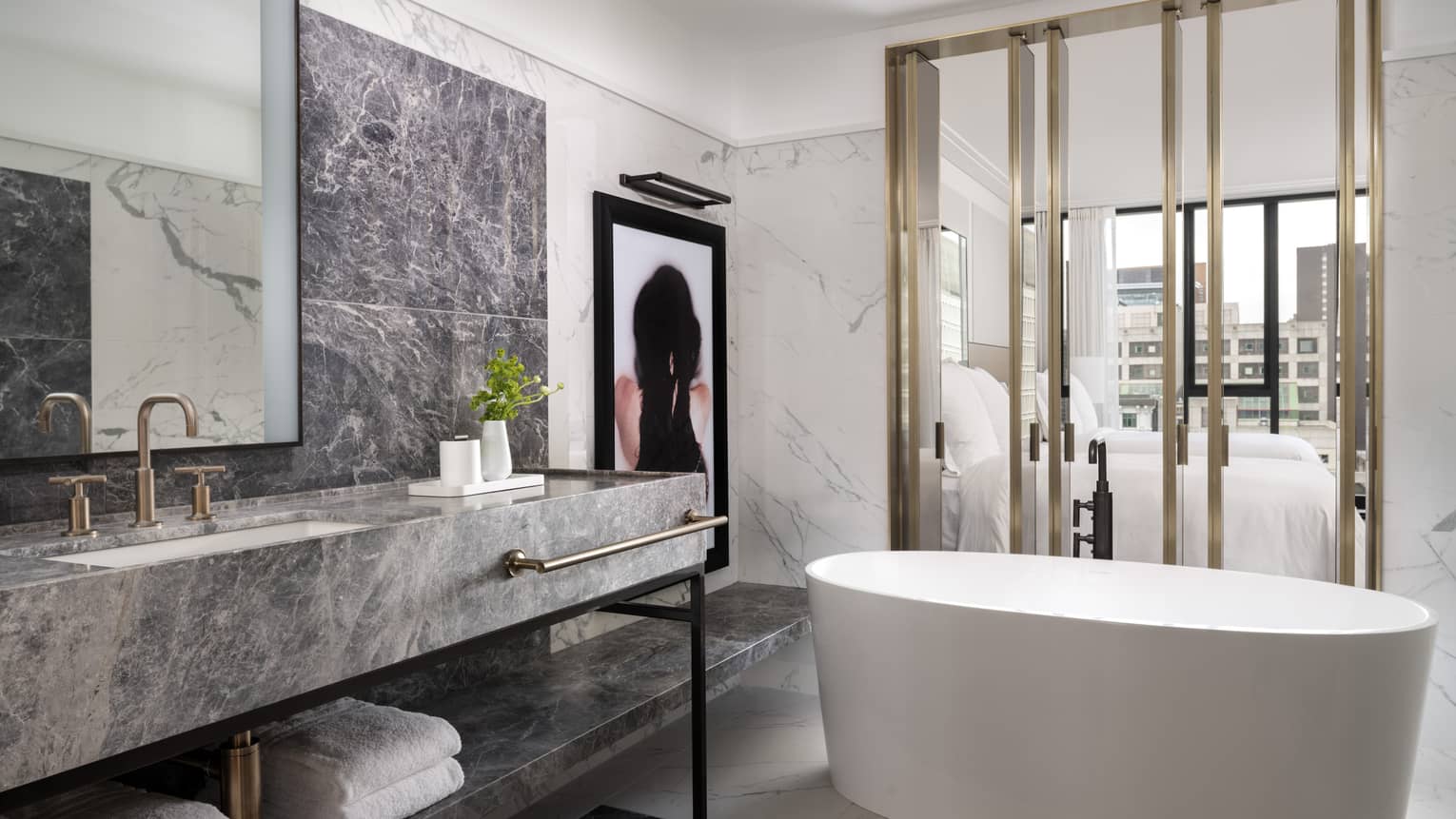 Spa-like guest bathroom with large white soaker tub, grey marbled vanity, modern artwork 