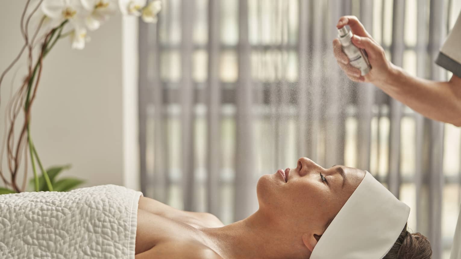 A woman being sprayed with mist during a spa treatment.