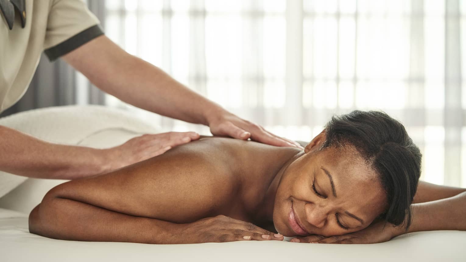 A person getting a massage in a well lit treatment room.