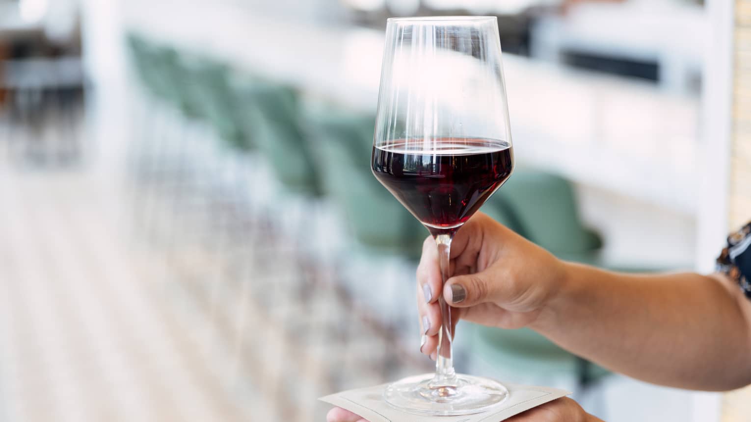 Hands hold a glass of red wine