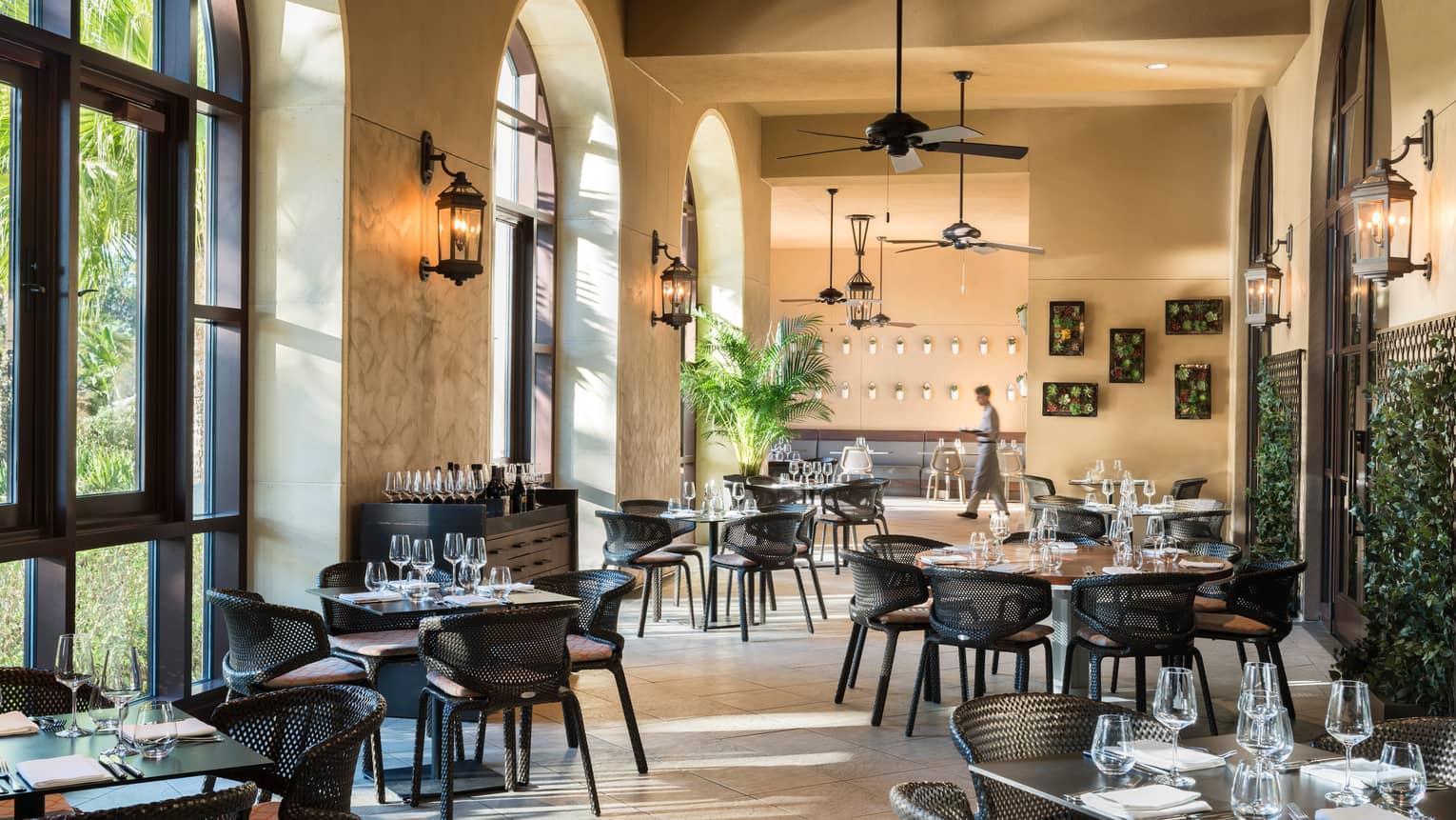 Ravello sunny dining room with tables, chairs under soaring ceilings, arched windows