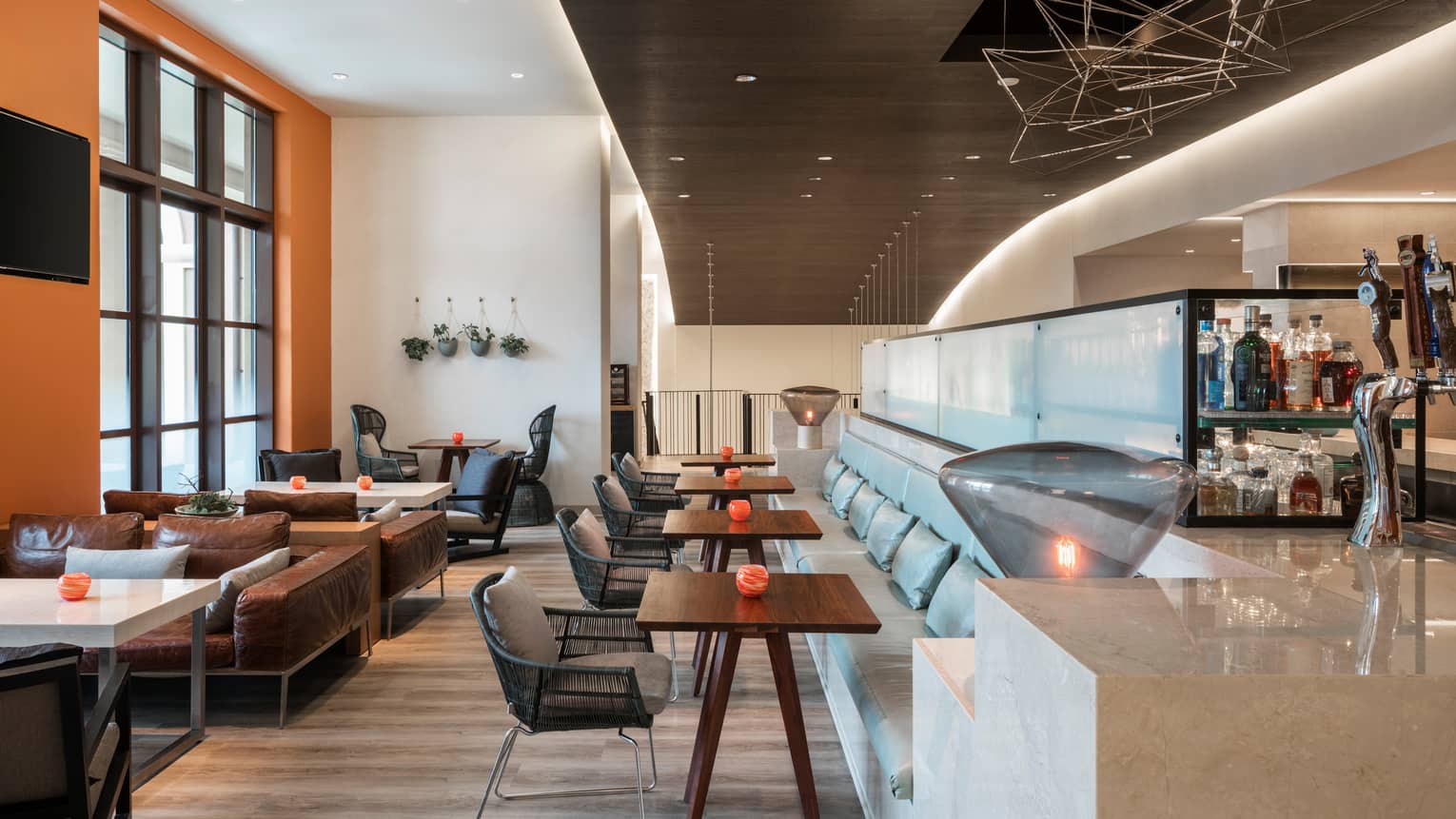 The Lobby Bar dining room with orange walls, accents, mid-century style furniture