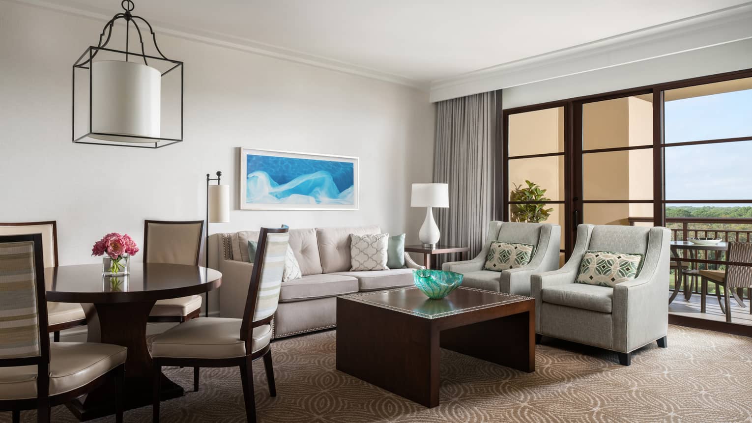 Living room with beige sofa, two arm chairs, wooden coffee table, round dining table and four chairs