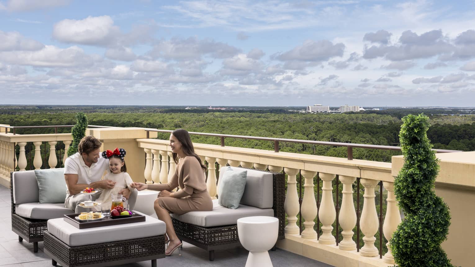 Man, woman and young girl sit on outdoor terrace