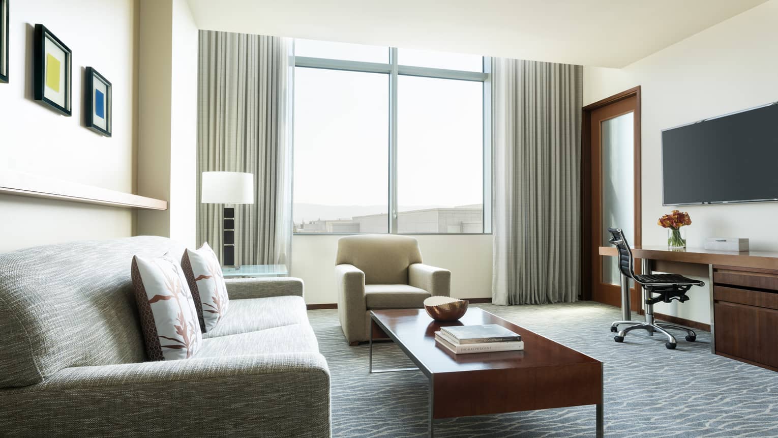 Executive Suite modern sofa, chair, wood coffee table with books, desk under TV