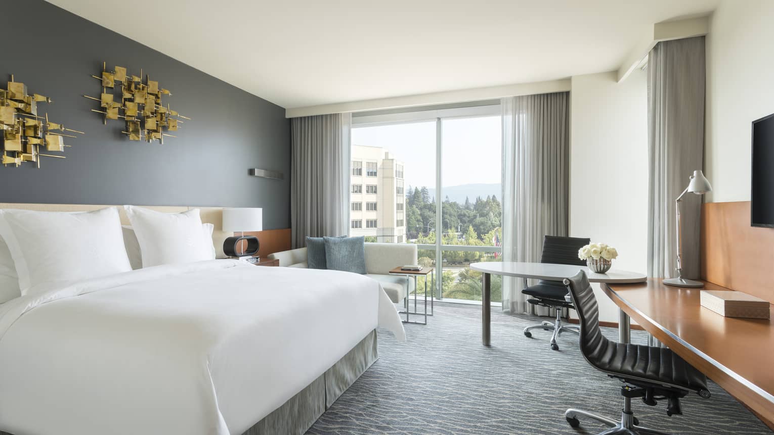 Premier Room bed under modern gold art, two desks, chaise by floor-to-ceiling window