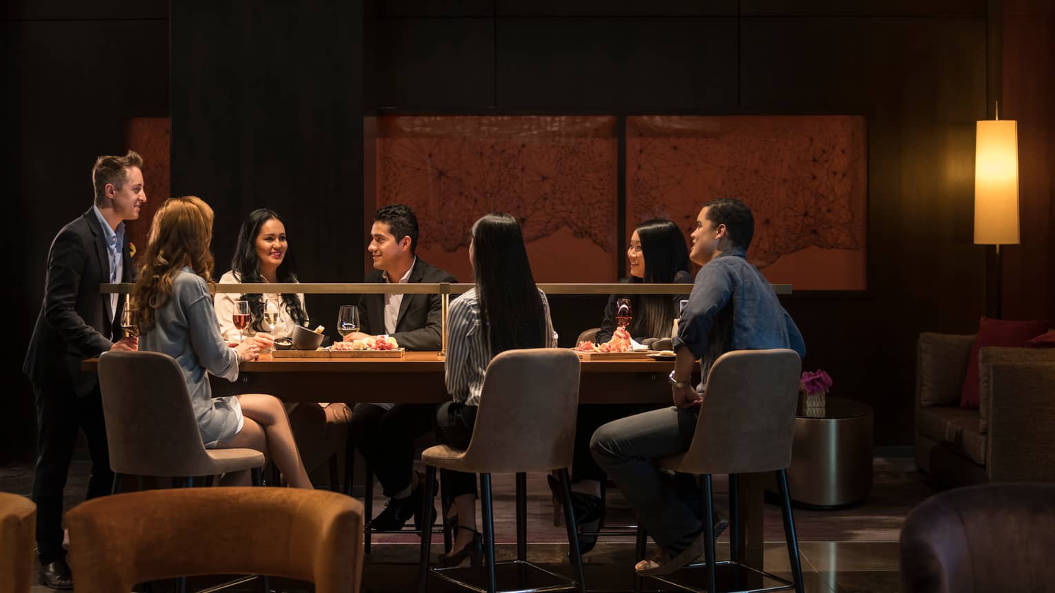 Quattro Lounge, smiling friends dressed in business attire eat, drink around long table