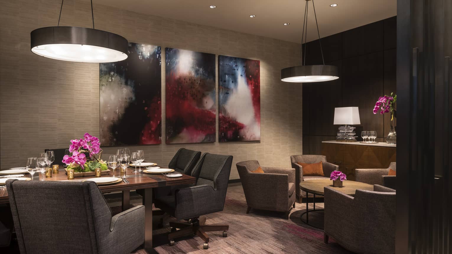 Plush grey dining chairs, art around table, seating area in dimly-lit meeting room