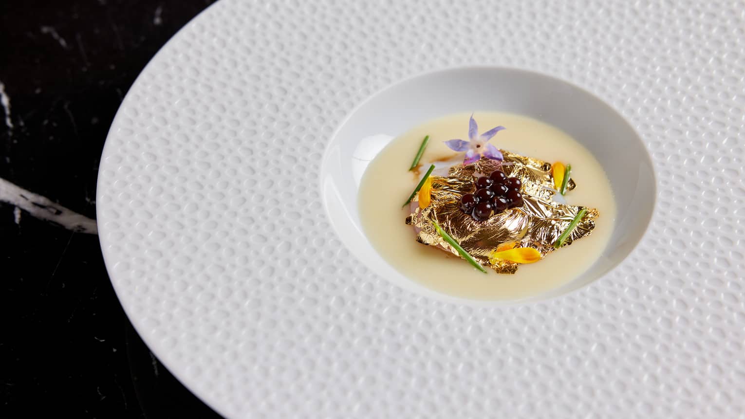 Food on a white plate on a dark table.