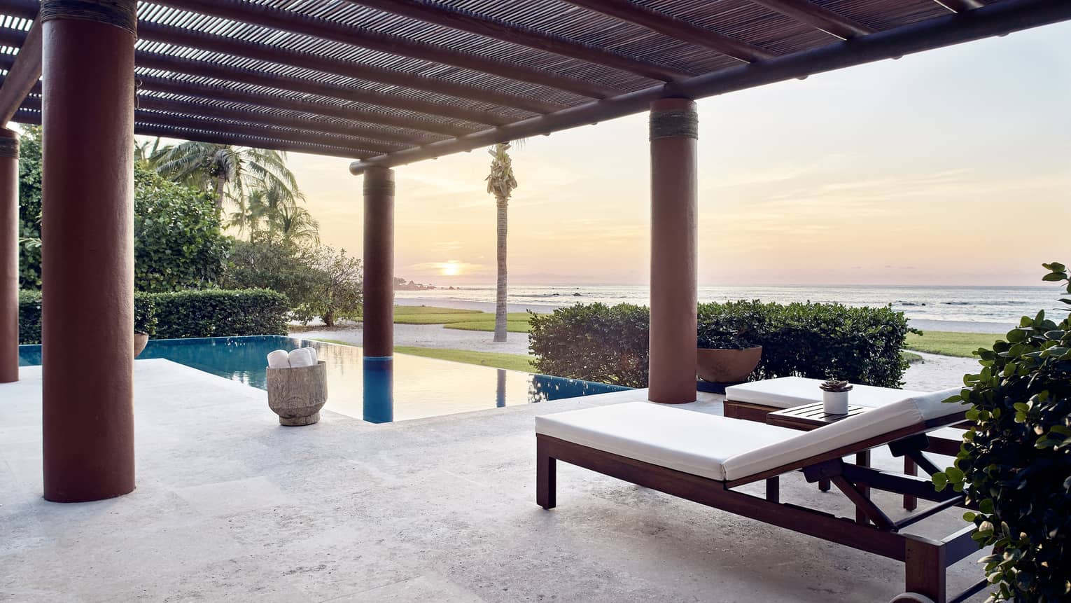Outdoor terrace with lounge chairs, private pool, sun setting over the sea