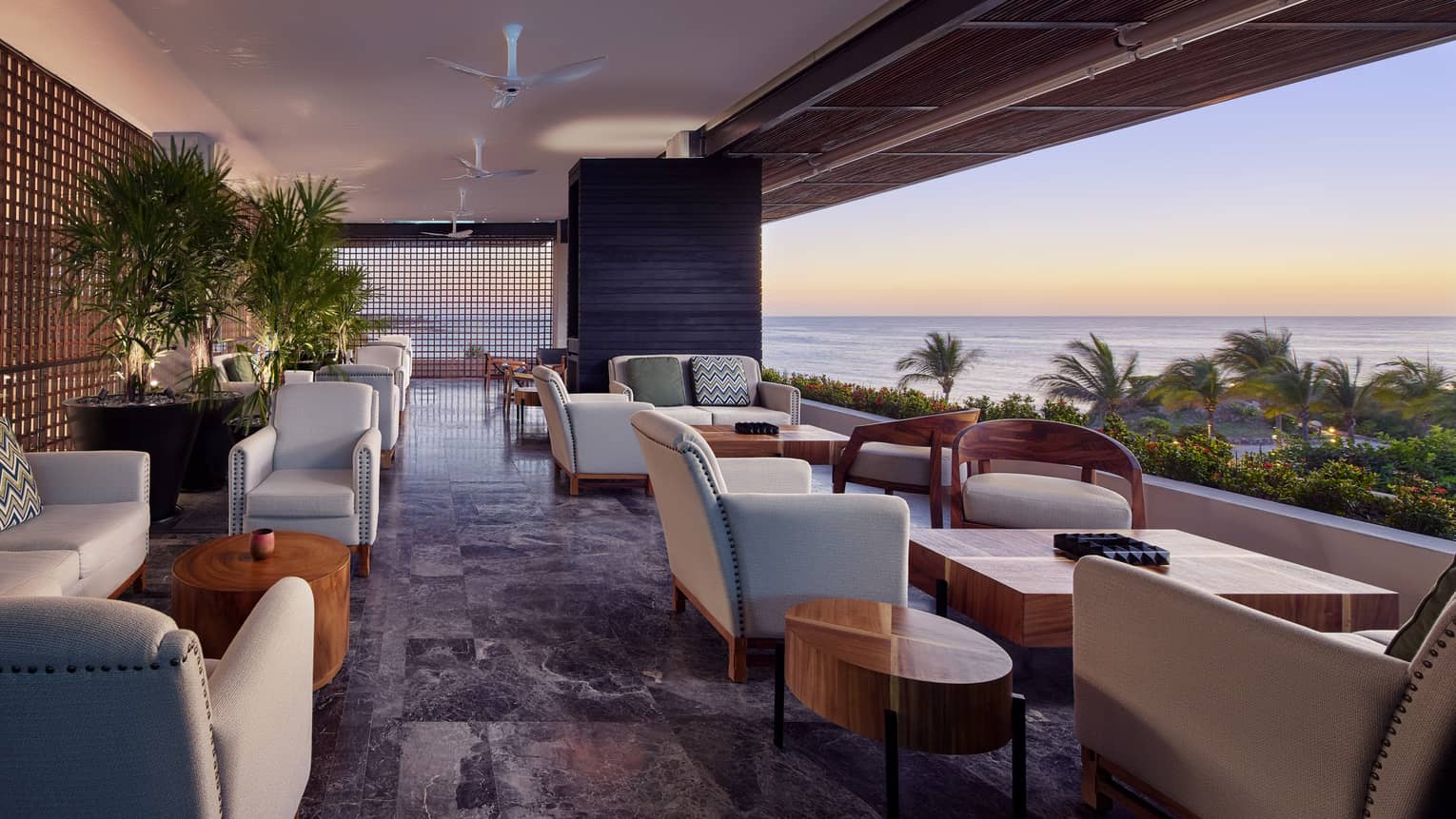 The sunset is visible through the open balcony of Dos Catrinas, lined with tables and leather chairs