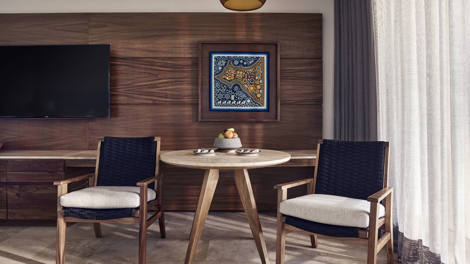 Small wooden table and two arm chairs, wooden wall and artwork