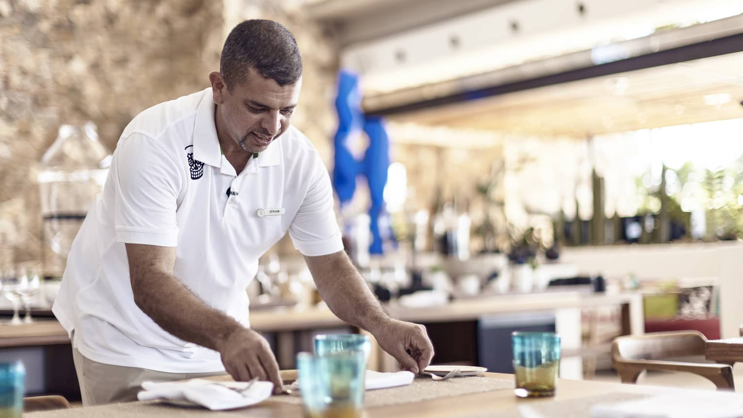 Efrain Cisneros sets table at resort restaurant