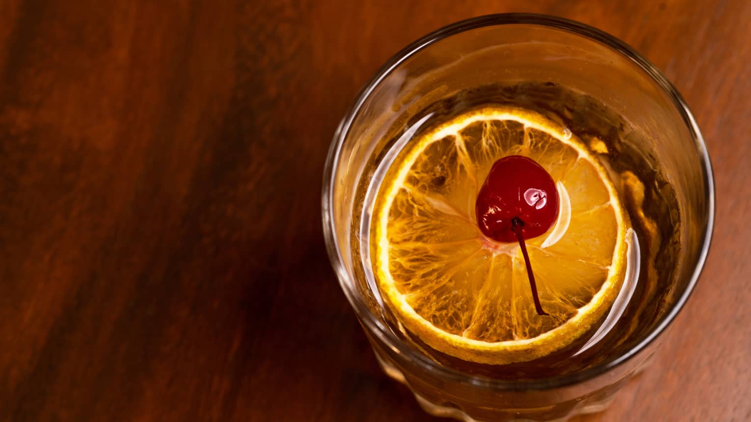 A cocktail with a cherry and orange slice in it.