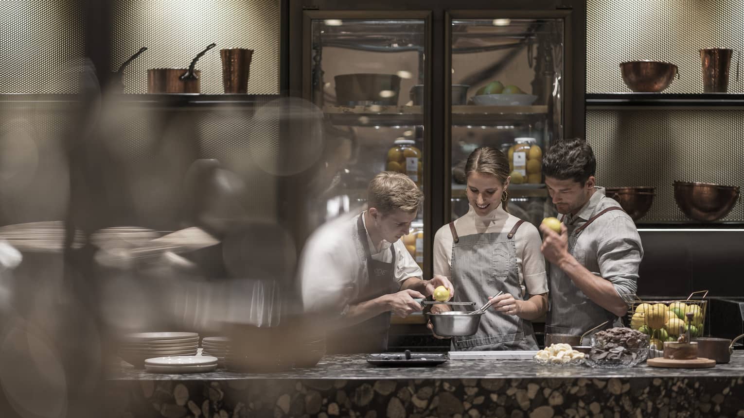 Chef grates lemon over bowl with couple at cooking class demonstration