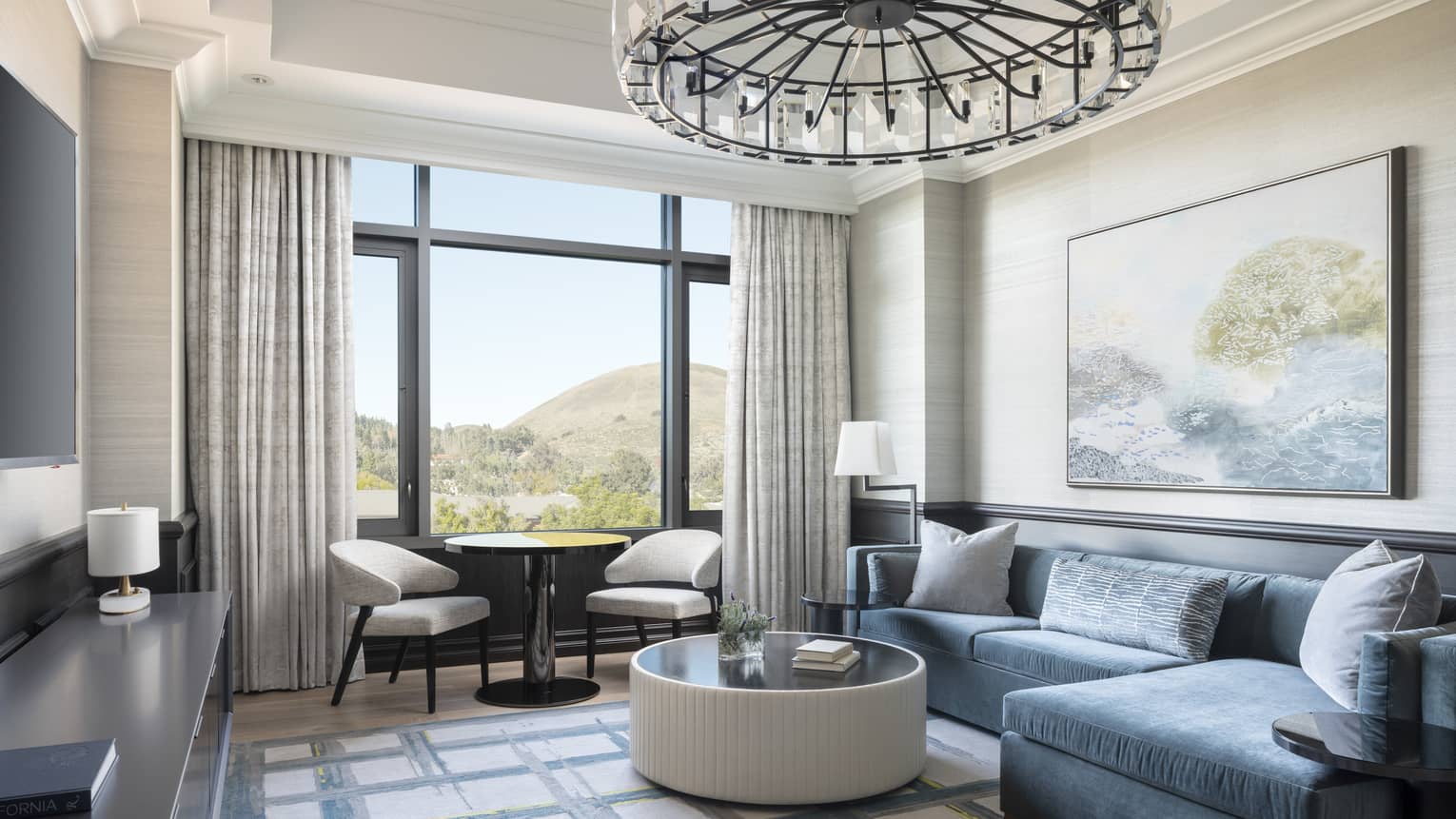 A separate sitting room in the Presidential Suite features a TV and a modern, dark blue L-shaped sofa