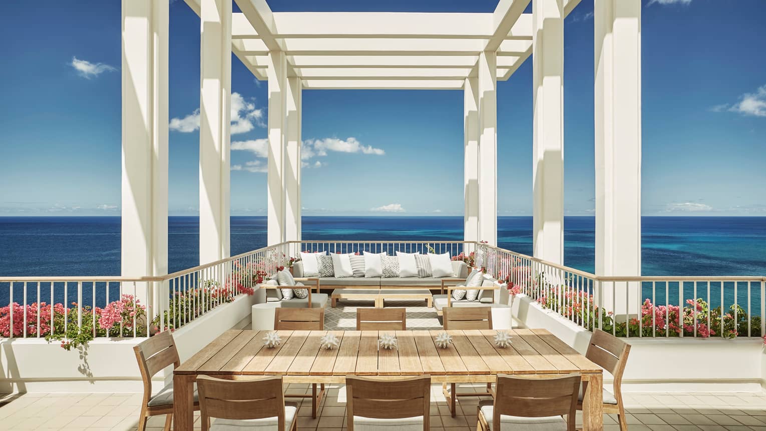 Penthouse Suite large patio dining table, seating area under white pergola, blue sky