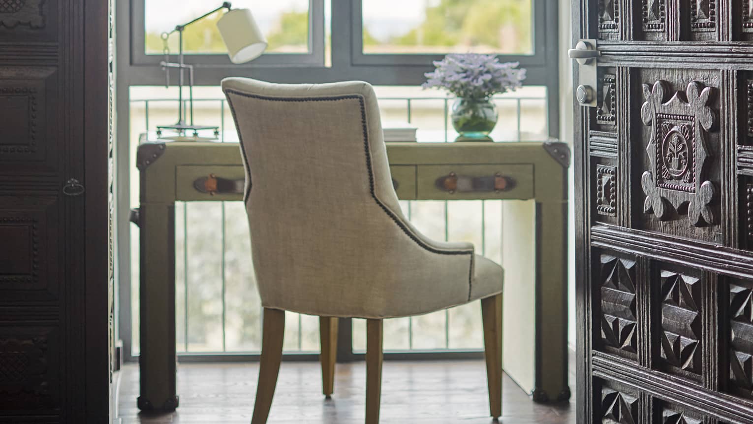 Desk and chair in front of window overlooking the garden, steepled ceiling with wooden rafters