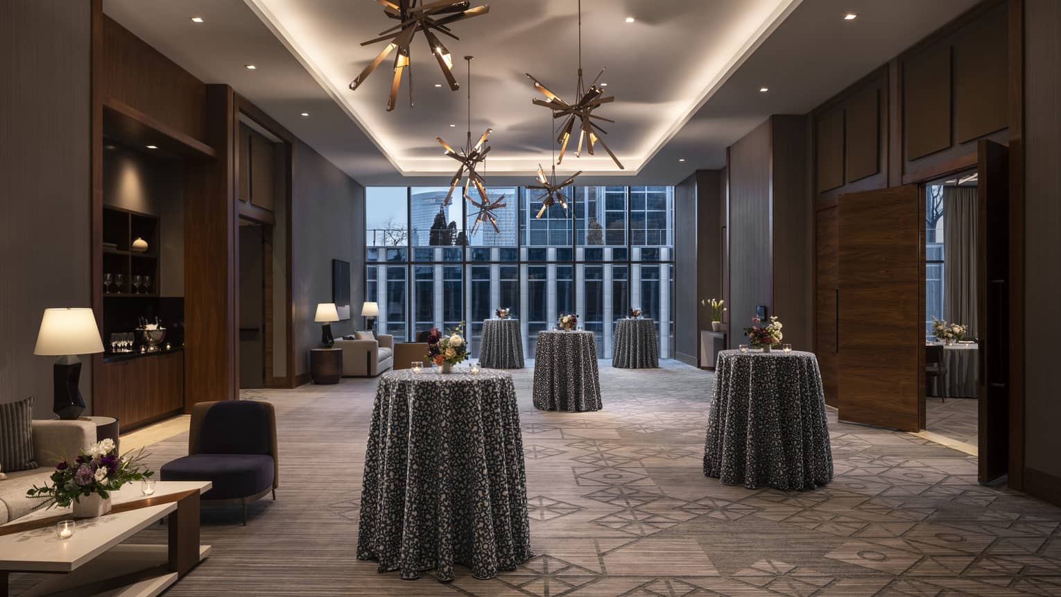 A large hall/entry area with standing tables and hanging lights.