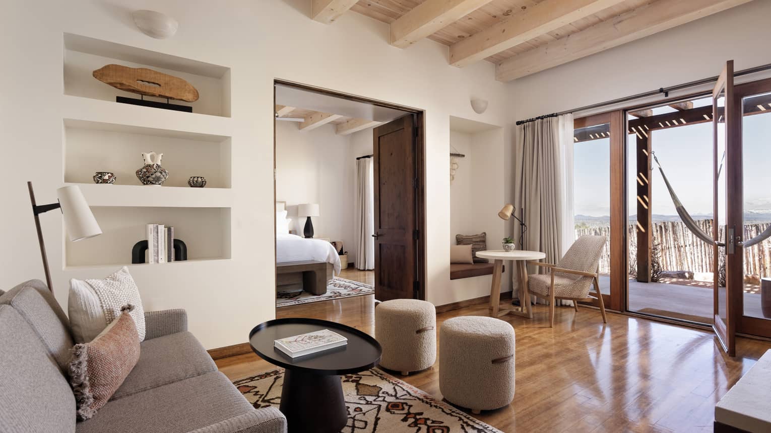A living room in a suite with a couch and coffee table, and hammock on the patio