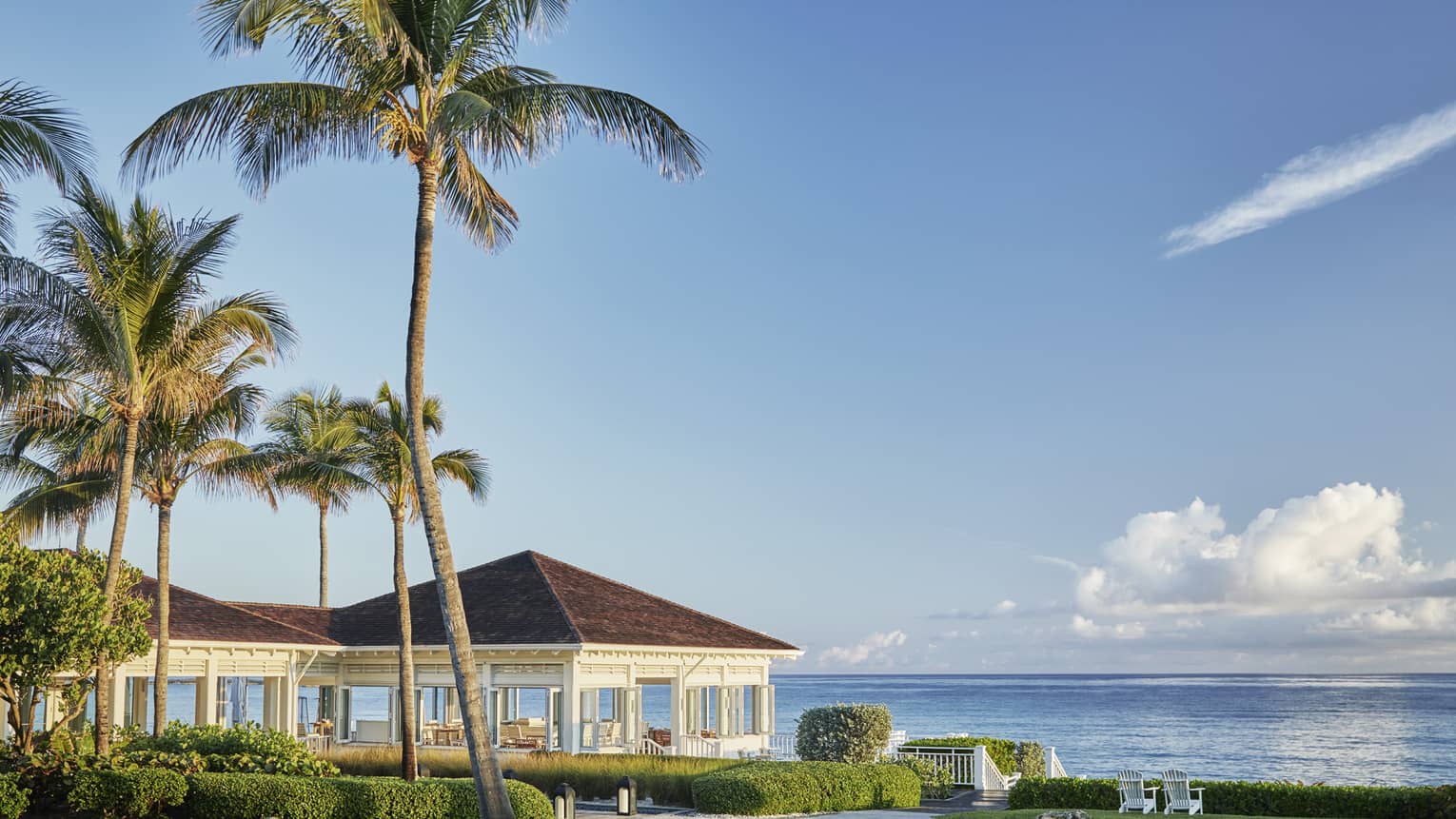 Oceanfront restaurant Dune's pavilions and palm trees, sunny skies over ocean