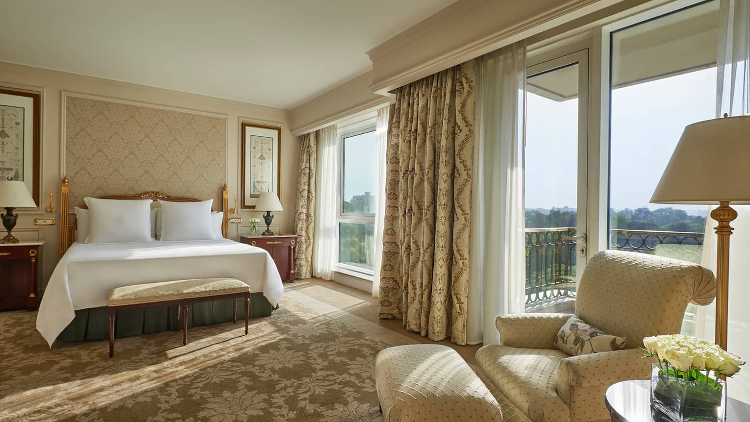 Deluxe Room bed, cream-coloured armchair beside sunny floor-to-ceiling patio door and window
