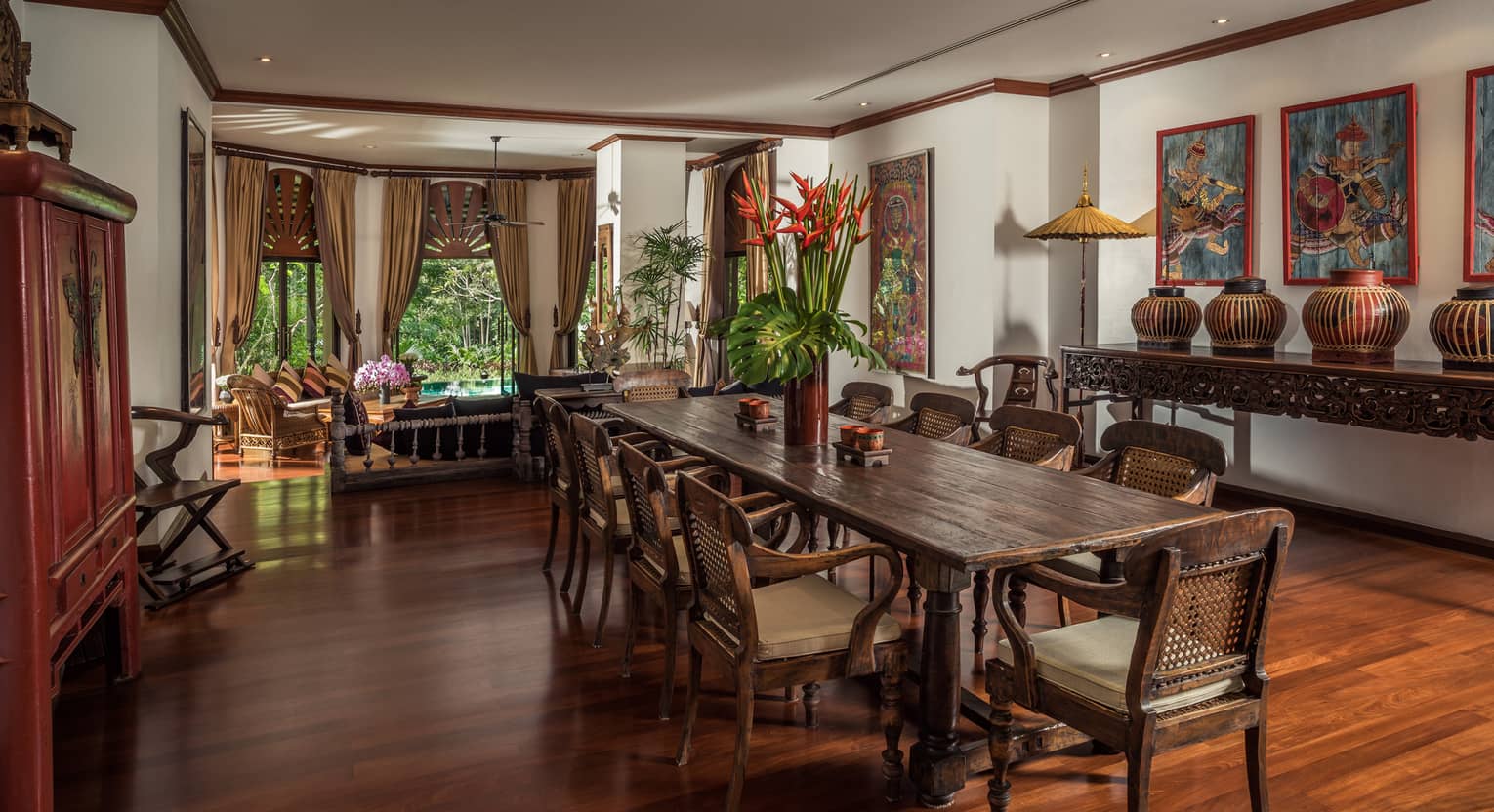 Long wood dining table with vase with tall tropical flowers in bright room