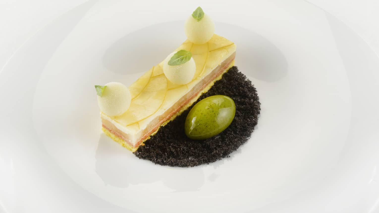 Green apple and lime ingot with extra virgin olive oil, basil and almonds pesto on white plate