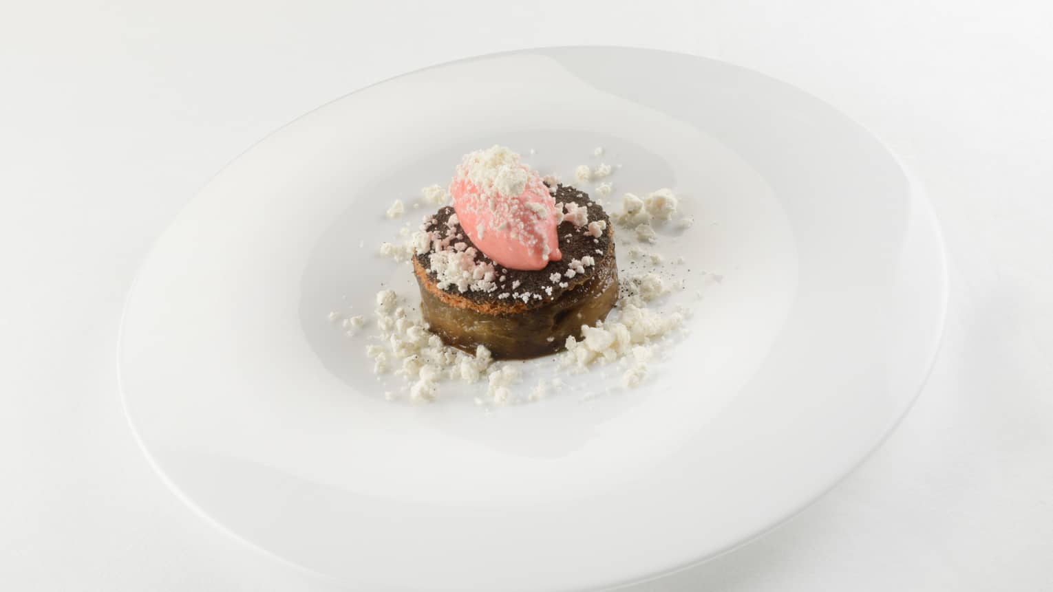 Circle of marinated eggplant plated on white dish
