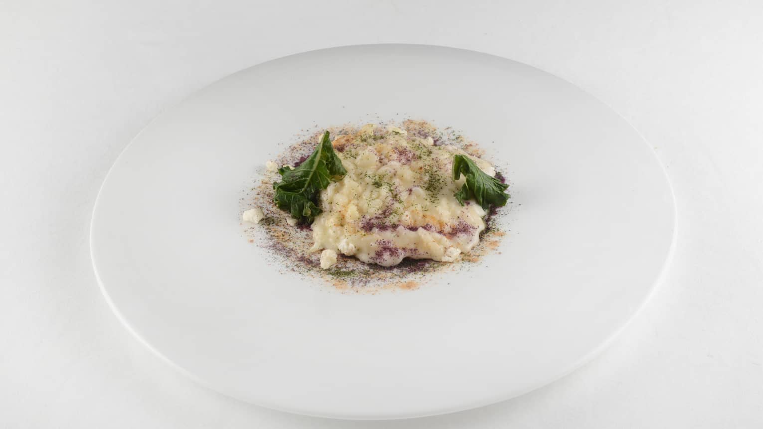 Lightly smoked risotto with seasonal cabbages on white plate