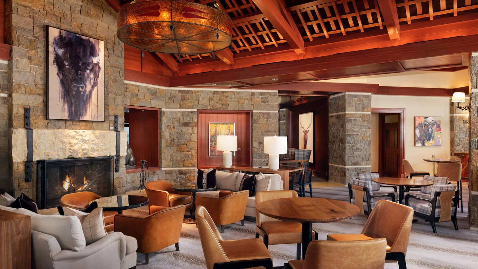 Luxury resort lounge and restaurant, with wooden beamed ceilings, stone walls, fireplace and leather chairs