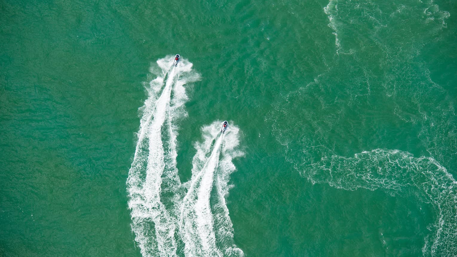 Aerial view of two jet skis, trails on water in ocean